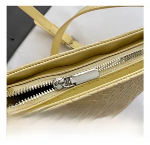 Détail de la fermeture éclair argentée sur un sac seau jaune à texture tissée