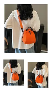 Small orange nylon crossbody bag for women with woven handle shown from back angles