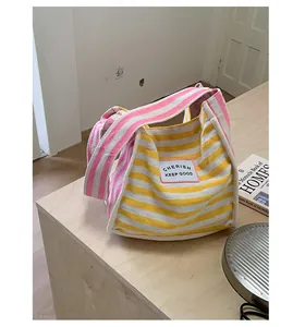 Detail of yellow and white striped canvas bag featuring a pink strap and fabric label