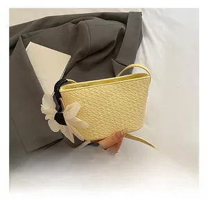 Détail du sac seau tissé jaune avec fleur et bandoulière sur un costume gris