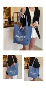 Detail of blue denim tote bag with dog print and red checkered bow shoulder strap