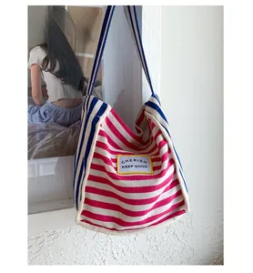 Detail of colorful striped canvas tote bag showing multi-color patchwork and slogan patch