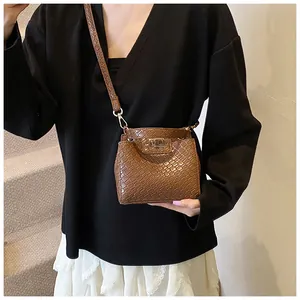 Détail d'un mini sac marron motif crocodile avec fermoir rotatif doré et fine bandoulière