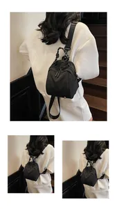 Rear view of a minimalist black nylon mini backpack worn with a white sweater