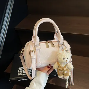 Chic pink leather woven barrel handbag with plush bear charm on stylish magazine background
