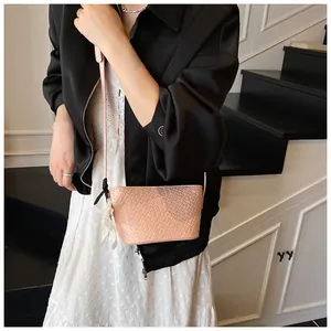 Détail du sac seau rose tressé avec foulard en soie porté par un mannequin au style décontracté