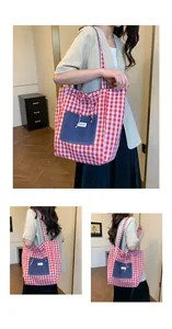 Detail of red and white checkered tote bag featuring a blue denim pocket and bow tie