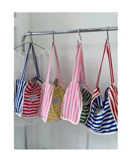 Row of four colorful striped canvas tote bags hanging on a rack showing various color schemes
