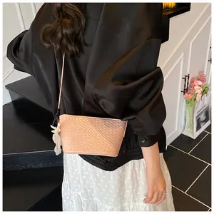 Détail du mini sac seau rose à texture tressée porté à l'épaule par un modèle
