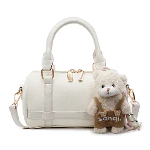 White woven boston bag with gold hardware and a cute teddy bear charm pendant