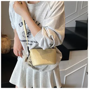 Détail du sac seau tissé jaune clair avec breloque fleur blanche et fine bandoulière