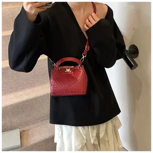 Détail du sac à main rouge à texture tressée avec fermoir doré et longue bandoulière