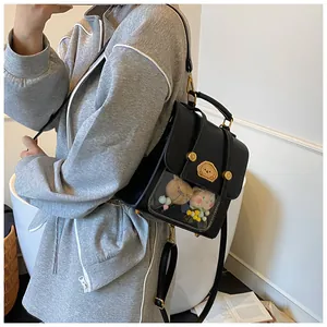 Détail d'un sac Ita noir avec fenêtre transparente montrant des peluches et ferrures dorées