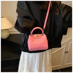 Détail du sac à main rose gaufré crocodile avec fermoir doré porté par un mannequin