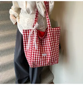 Detail of red and white checkered canvas tote bag with a white lace bow decoration