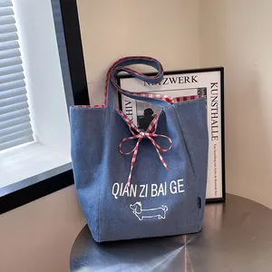 Large denim tote bag with red plaid lining and dachshund print on a metal table