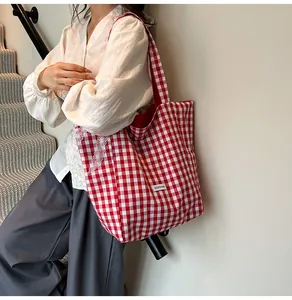 Close-up of red gingham canvas tote bag with white lace trim carried on the shoulder