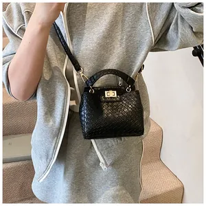 Détail du sac noir effet crocodile avec fermoir rotatif doré et anse supérieure ronde
