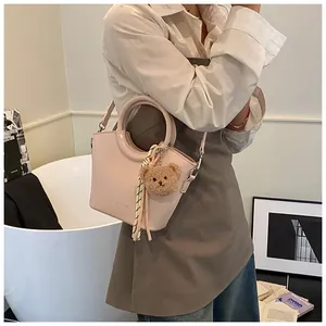 Detail of light pink tote bag with circular handle and brown plush bear charm