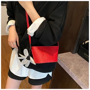 Détail du sac seau tissé rouge avec grand charme de fleur blanche 3D pour femmes