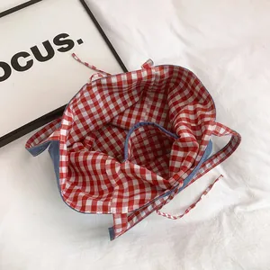 Reversible striped denim tote bag with red checkered lining and interior pocket