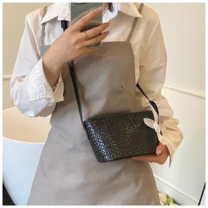 Détail du sac seau tressé noir avec nœud blanc élégant et fine bandoulière réglable
