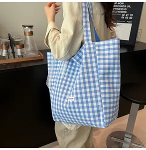 Close-up of blue plaid canvas tote bag featuring white lace trim and lilhouse label