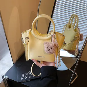 Chic light yellow leather basket bag with teddy charm shown in front and back mirror views