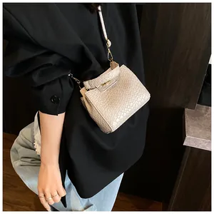 Détail du sac à bandoulière beige effet croco avec un fermoir tournant en métal doré