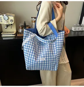Detailed close-up of blue and white checkered canvas tote with lace bow and brand label