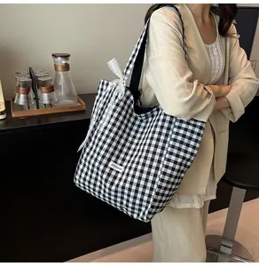 Detail of canvas tote bag with black and white gingham pattern and white lace bow