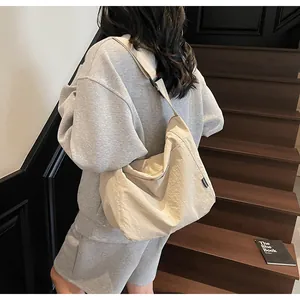 Detailed view of the beige canvas tote bag showing the side fashion label and draped texture