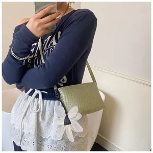 Détail d'un sac bandoulière tissé vert clair avec un grand charm fleur de marguerite