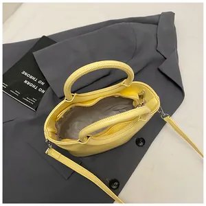 Vibrant yellow fashion bucket bag with top handle and detachable strap on a blazer
