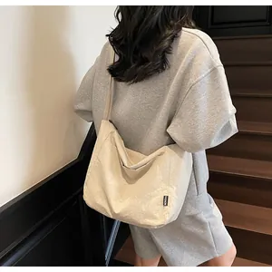 Detail of beige canvas tote bag showing fashion tag and durable texture on model