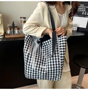 Detail of black and white checkered canvas tote bag with delicate white lace trim