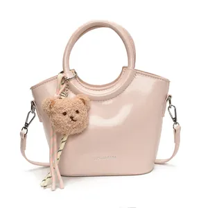 Light pink patent leather basket bag with round handles and cute plush bear charm