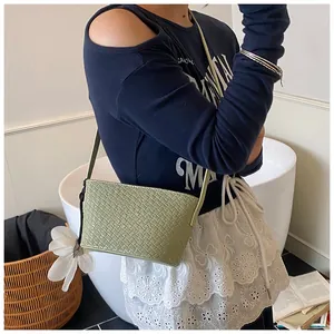 Détail du sac seau tissé vert sauge avec un accessoire de charme floral blanc
