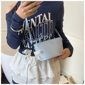 Détail du sac seau bleu clair à motif crocodile avec un charmant pendentif floral blanc