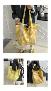 Detail of yellow checkered canvas tote bag with white lace bow and reversible design