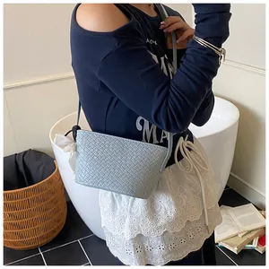 Détail du sac seau bleu clair montrant la texture tressée et le nœud décoratif noir