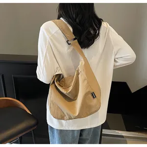 Detail of khaki canvas tote bag with fashion label and adjustable wide shoulder strap