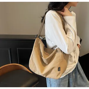 Detail of khaki canvas tote bag showing fashion tag and adjustable shoulder strap