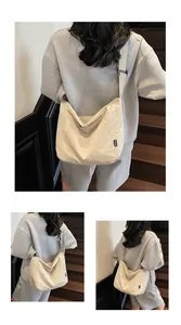 Close-up of cream canvas tote bag showing side fashion label and adjustable strap detail