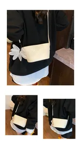 Détail d'un sac seau tissé crème avec charm fleur vaporeuse et bandoulière élégante