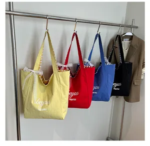 Detail of four colorful canvas tote bags with lace bows and stylish plaid inner lining
