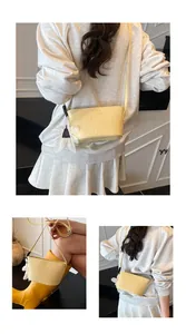 Détail du sac seau tissé jaune clair avec breloque fleur et bandoulière réglable