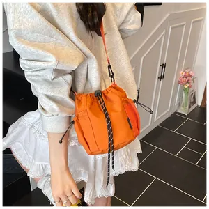 Detail der orangen Bucket Bag mit schwarzem Kordelzug und seitlicher Netztasche für Damen