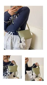 Détail du sac à bandoulière tissé vert avec une grande breloque fleur en tissu blanc déco