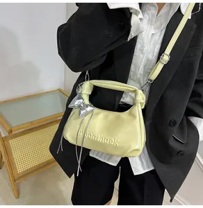 Détail du sac jaune avec logo gaufré moonshaek et pendentif nœud argenté chic